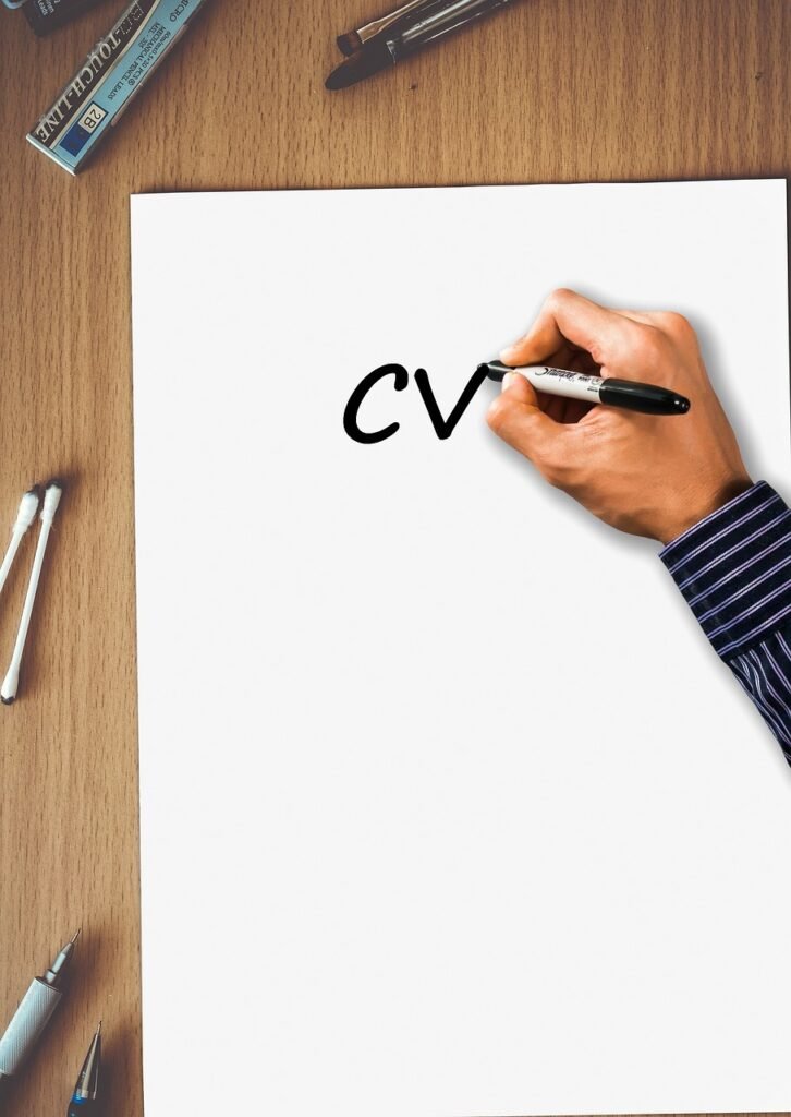 Imagem de mão escrevendo 'CV' em papel representando revisão de currículo para entrevista de emprego